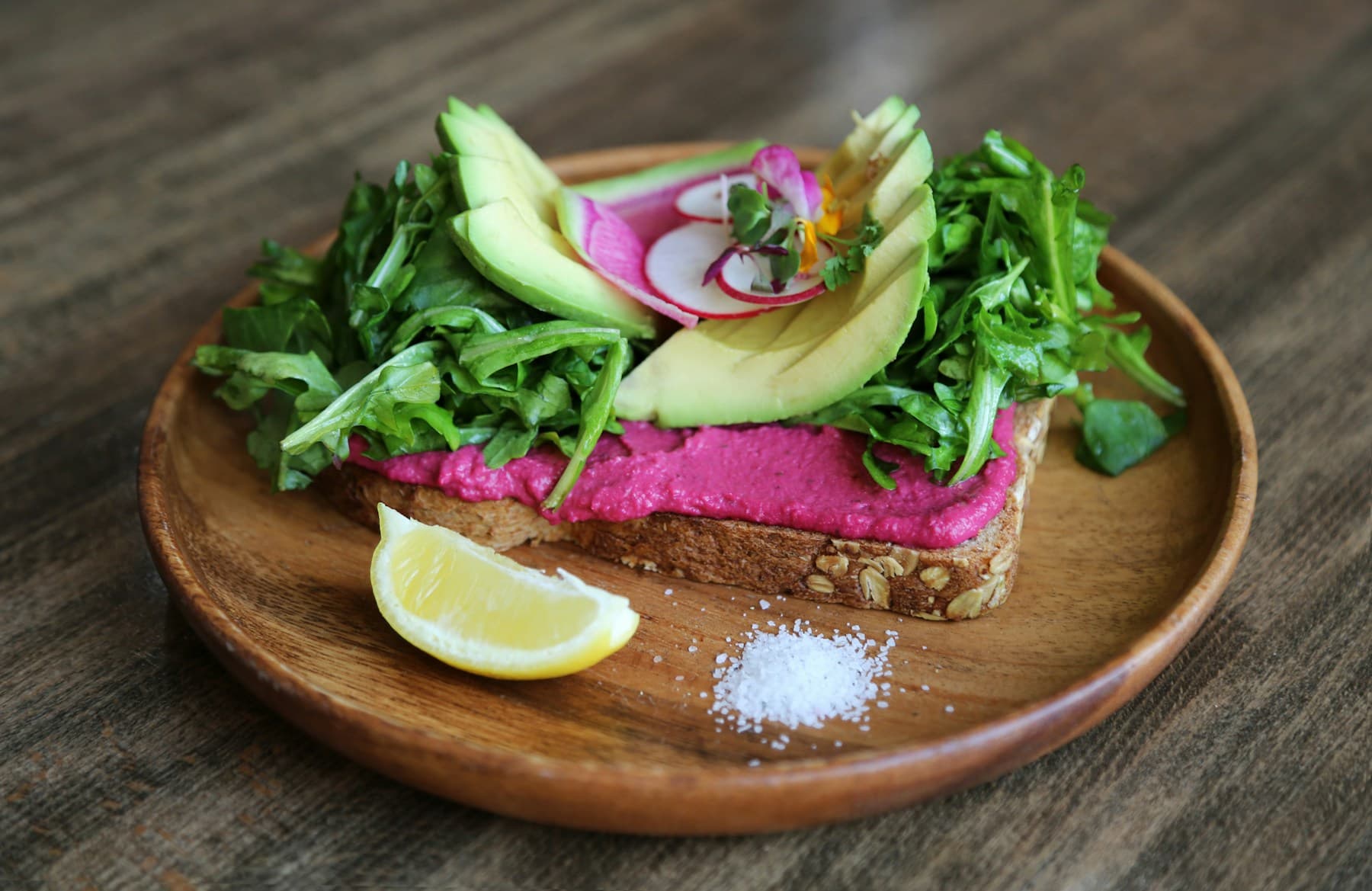 Avocado, greens and beet hummus served on seeded toast